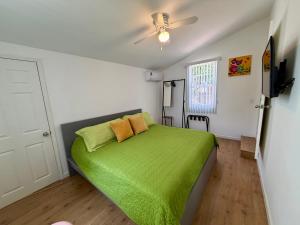 a bedroom with a green bed with a ceiling fan at Yellow Beachfront Dream Home in Rosarito Beach