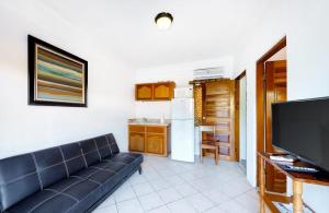 a living room with a couch and a flat screen tv at Affordable Suite with WiFi Partial AC Shared Rooftop Deck Pool and Grill in Caye Caulker +18 photos
