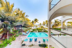 an indoor balcony with a swimming pool and palm trees at Relaxing condo with shared pool ocean views partial AC & WiFi in San Pedro