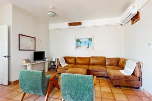 a living room with a brown leather couch and chairs at Charming beachfront condo with a kitchenette shared pool WiFi & beach access in Placencia