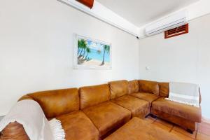 a brown leather couch in a living room at Charming beachfront condo with a kitchenette shared pool WiFi & beach access in Placencia