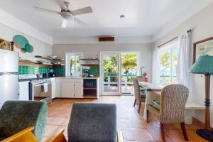 a kitchen with a table and chairs and a kitchen with white appliances at Charming beachfront condo with a kitchenette shared pool WiFi & beach access in Placencia