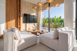 a living room with two white chairs and a tv at Ardhana Villas - Luxury Pool Stay with Scenic Views in Ungasan