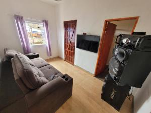 a living room with a couch and a flat screen tv at mirante por do sol in São Thomé das Letras