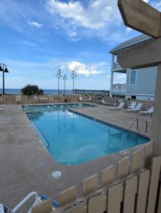 a swimming pool with chairs and the ocean in the background at Seven Seas in Kure Beach