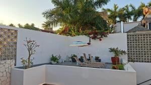 a patio with chairs and an umbrella on a white wall at Hotel Diamante Sayulita in Sayulita