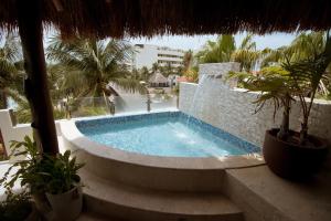 a swimming pool in a resort with trees and a building at Cuxos Hotel Beachfront in Isla Mujeres