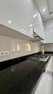 a kitchen with white cabinets and a stove top oven at Plage & Confort in Fnidek