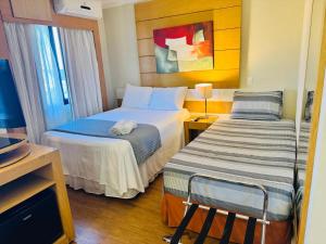 a hotel room with two beds and a window at Flat de Luxo Aeroporto Congonhas - Hotel in São Paulo