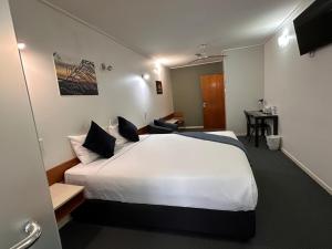 a hotel room with a white bed and a desk at Ayr Traveller's Motel in Ayr +95 photos