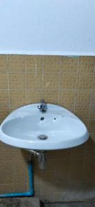 a white sink in a bathroom with a tiled wall at Urban Nest Hostel in Bangkok