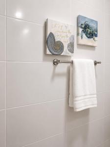 a white bathroom with a towel and some pictures at HERGOZ Apartamentos in Cayetano Germosén