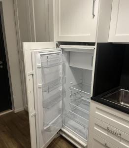 an empty refrigerator with its door open in a kitchen at Riverside Apartment Tartu in Tartu