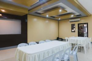 a room with white tables and chairs and a projection screen at Jared Suites in Upper Digos