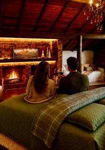 a man and woman sitting on a bed in front of a fireplace at Casa Holanda - luxury guesthouse in Teresópolis +36 photos
