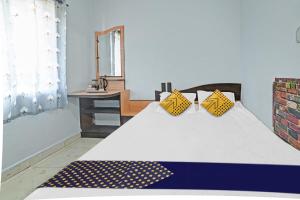 a bedroom with a bed with yellow pillows and a mirror at Hotel O SS in Chandrapur