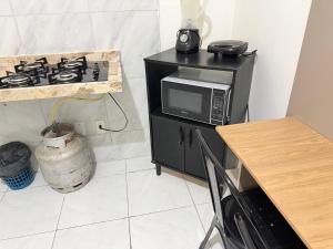 a kitchen with a microwave and a stove at Ap no Derby com garagem e ar in Sobral