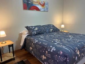 a bedroom with a bed with a blue comforter and two lamps at Apart Hotel Colon in La Serena
