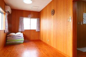 ein Wohnzimmer mit Holzboden und einem Fenster in der Unterkunft アトムハウス in Okinawa