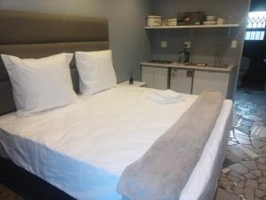 a large bed with white sheets and pillows in a room at Lifeshed in Johannesburg