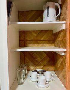 a cupboard with cups and saucers on a shelf at Apart Hotel Colon in La Serena