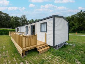 a tiny house with a porch and a deck at Comfortable caravan in a green setting in Vierhuizen