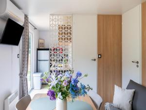 a living room with a vase of flowers on a table at Comfortable caravan in a green setting in Vierhuizen