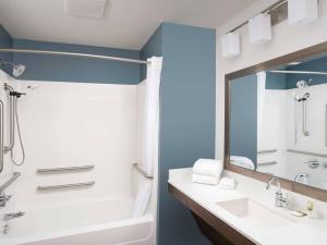 a bathroom with a tub and a sink and a mirror at WoodSpring Suites in Glendale +17 photos