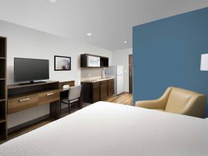 a hotel room with a bed and a desk with a television at WoodSpring Suites in Glendale