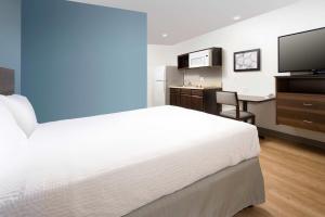 a bedroom with a bed and a desk and a television at WoodSpring Suites in Glendale