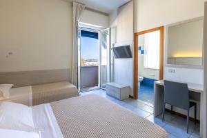 a hotel room with two beds and a desk and a window at Hotel Astoria in Fano +111 photos