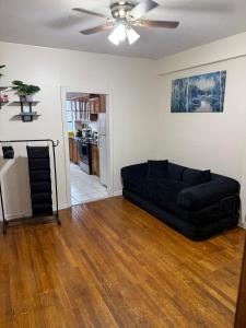a living room with a black couch and a ceiling fan at Madison - Shared apartment in New York