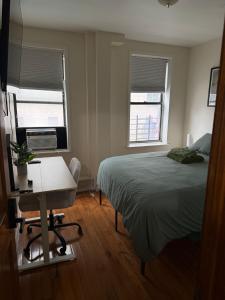 a bedroom with a bed and a desk and two windows at Madison - Shared apartment in New York