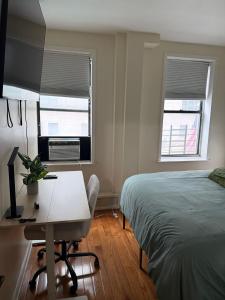 a bedroom with a bed and a desk and two windows at Madison - Shared apartment in New York