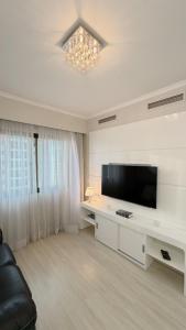 a white living room with a television and a couch at Ibirapuera Privilege - Suíte Deluxe Moema in São Paulo
