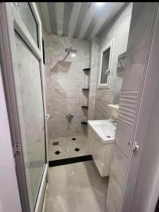 a white bathroom with a shower and a sink at اقامة حسن الجوار in Oran