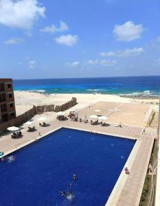 a large blue swimming pool next to a beach at Asala Village, Blue Bay Resort, Marsa Matrouh in Marsa Matruh