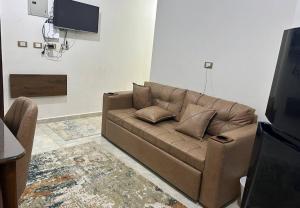 a living room with a brown couch and a tv at Asala Village, Blue Bay Resort, Marsa Matrouh in Marsa Matruh