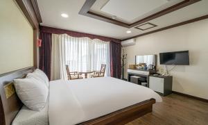 a bedroom with a large white bed and a desk at Mobydick Hotel in Yangyang