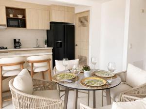 ein Esszimmer mit einem Tisch, auf dem Teller und Weingläser stehen in der Unterkunft Apartamento nuevo en Cartagena, Serena del Mar - INAWA in Cartagena de Indias + 31 Fotos