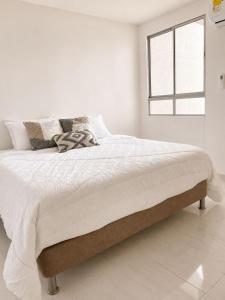 ein weißes Schlafzimmer mit einem großen Bett und einem Fenster in der Unterkunft Apartamento nuevo en Cartagena, Serena del Mar - INAWA in Cartagena de Indias