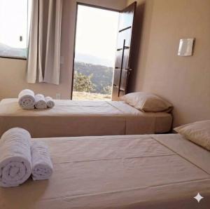 two beds in a room with towels on them at Pousada altavista acuruí in Itabirito
