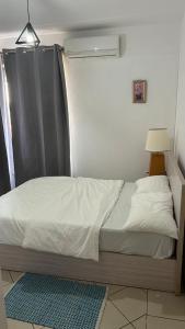 a small bed in a room with a window at RESIDENCE CYBERVILLAGE THREE ROOMS Apartment in Ebene