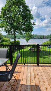a deck with a table and a chair and a view of the water at Chalet Ohana in Adstock