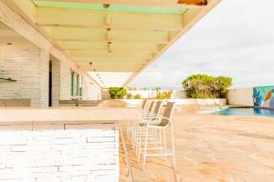 Eine Reihe Stühle auf einer Terrasse neben einem Swimmingpool in der Unterkunft Wyndham Macae in Macaé
