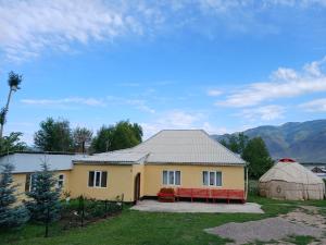 a yellow house with a red bench in front of it at Bugu Too Guest House in Kaindy