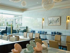 a waiting room with chairs and tables and chandeliers at Hotel Plaza Osaka in Osaka