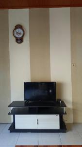 a black entertainment center with a clock on a wall at Yus homestay in Bukittinggi