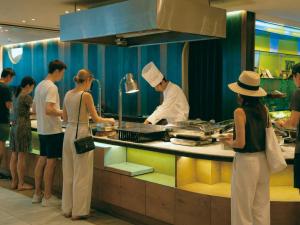 a group of people standing in a kitchen preparing food at Hotel Plaza Osaka in Osaka