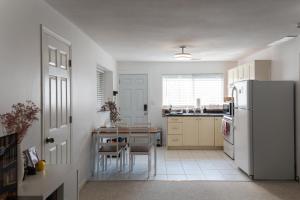 a white kitchen with a table and a refrigerator at Cheng Rental in Surrey